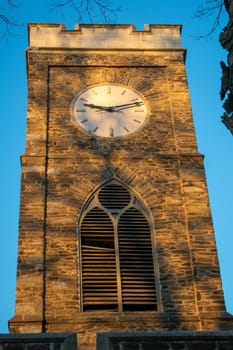 A Clocktower bathed in glowing orange sunlight with shadows from a tree