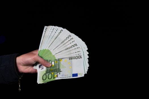 Hand counting holding and showing euro money or giving money. World money concept, 100 EURO banknotes EUR currency isolated on black with copy space. Concept of rich people, saving or spending money