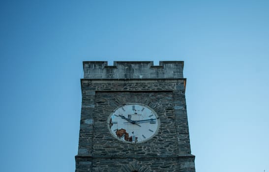 A Church's Cobblestone Clock Tower on a Clear Blue Sky