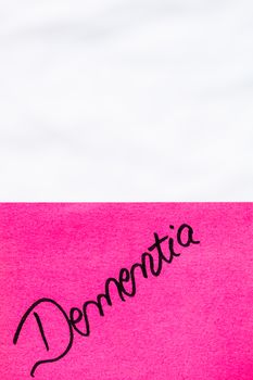 Dementia handwriting text close up isolated on pink paper with copy space. Writing text on memo post reminder