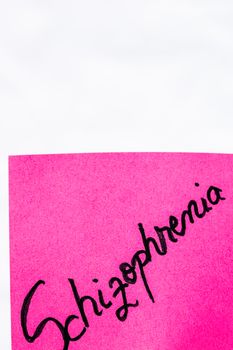 Schizophrenia handwriting text close up isolated on pink paper with copy space. Writing text on memo post reminder