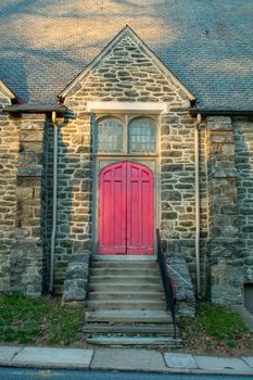A Bright Red Door in a Cobblestone Church Wall With Steps Leading Up to It