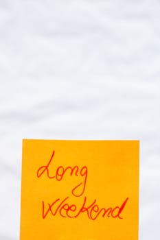 Long weekend handwriting text close up isolated on orange paper with copy space.