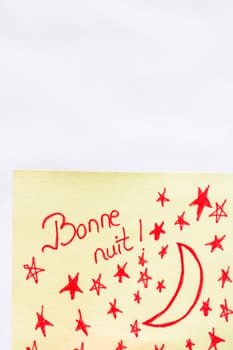 Bonne nuit (good night) handwriting text close up isolated on yellow paper with copy space.