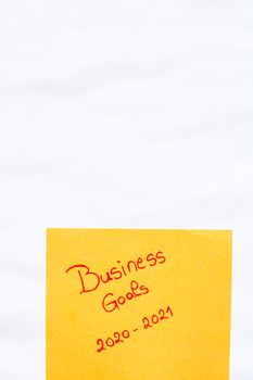 Business goals 2020-2021 handwriting text close up isolated on orange paper with copy space. Writing text on memo post reminder