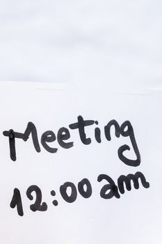 Meeting handwriting text close up isolated on white paper with copy space. Writing text on memo post reminder