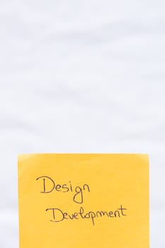 Design development handwriting text close up isolated on orange paper with copy space. Writing text on memo post reminder