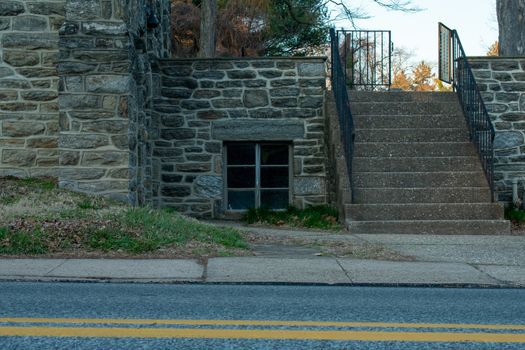 A window In a cobblestone church wall with steps next to it