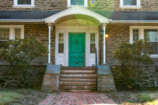 A Teal Front Door on a Suburban Home With a Brick Path Leading Up to It