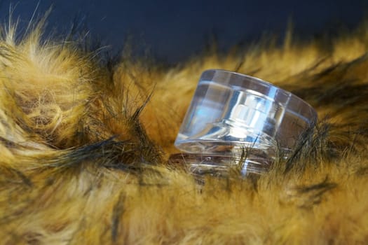 perfume bottle in yellow fur on a black background close-up