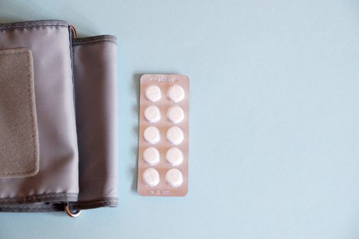 tonometer and pills on blue background, view from above.