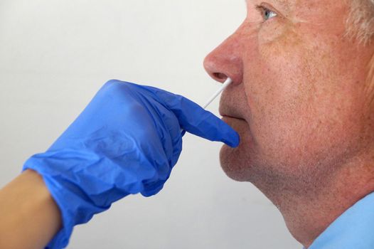 the doctor takes a test for coronavirus from the man's nose.