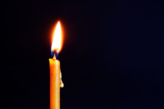 burning wax candle close up on dark background.