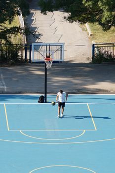 Varna, Bulgaria - August, 22, 2020: young man training with a ball on an outdoor basketball court