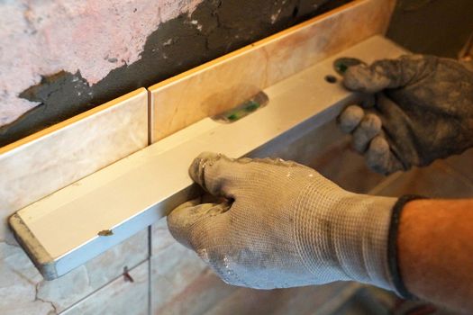 the man checks the level of evenness of the tiles.