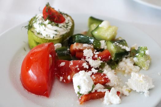 tomato, zucchini and bell pepper with feta cheese on a white plate.