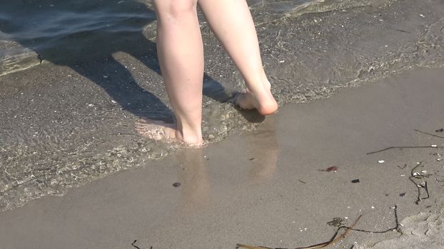 Young female feet walking in the shallow water at a baltic sea beach