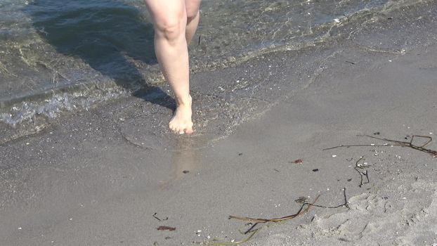 Young female feet walking in the shallow water at a baltic sea beach