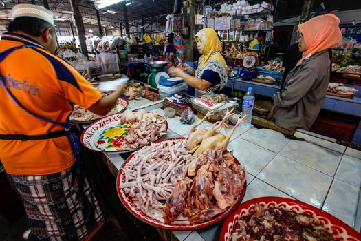 Khao Lak, Thailand - February 22, 2016:  Unknown woman buying fresh chicken meat from local merchant on market. Thai cuisine is renowned for its tasty food.