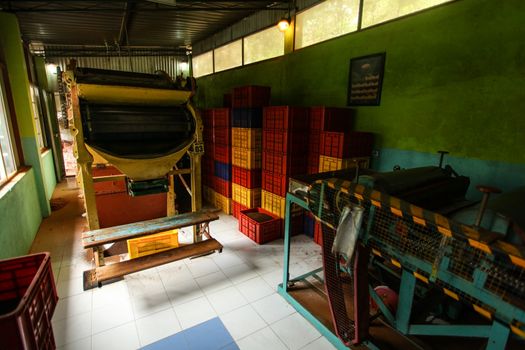 Kandy, Sri Lanka - April 12th, 2017: Empty room with tea dryer machine at Kadugannawa Tea Factory, plastic boxes with processed tea in back. Some of finest tea in the world is produced in Sri Lanka