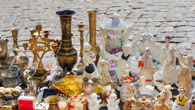 Antiques on the old pavement of the old town. Antique souvenirs sold on weekends at the flea market. Spontaneous antiques market. Vintage antiques items. Antique souvenirs figurines vase. Soviet Union