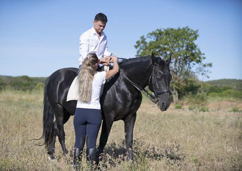  riding teenager are training her black horse with teacher