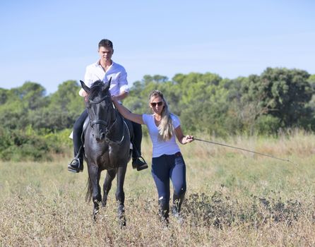  riding teenager are training her black horse with teacher