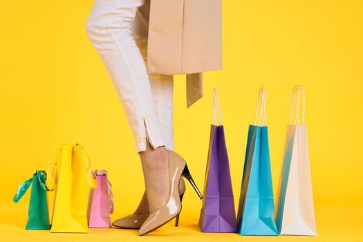 female feet in shoes packs shopping lifestyle yellow isolated background. High quality photo