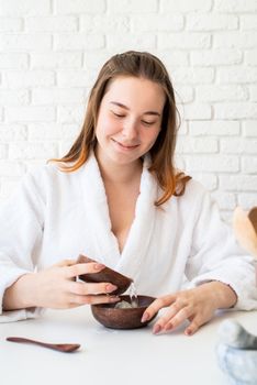 Spa and wellness. Natural cosmetics. Self care. Young caucasian woman wearing bathrobes doing spa procedures using natural cosmetics