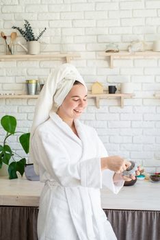 Spa and wellness. Natural cosmetics. Self care. Happy young woman applying face scrub on her face in her home kitchen