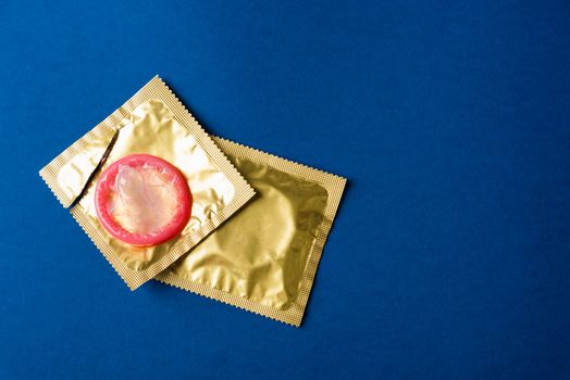 World sexual health or Aids day, Top view flat lay condom in wrapper pack is tear open, studio shot isolated on a dark blue background, Safe sex and reproductive health concept