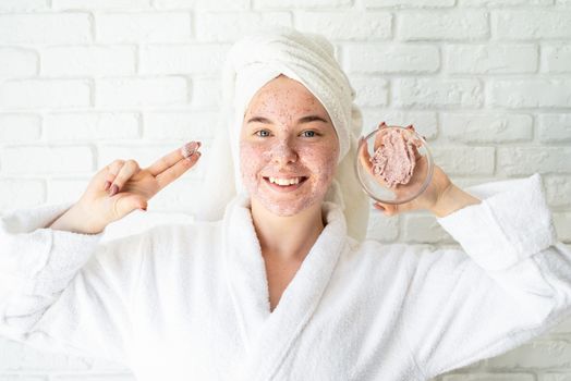 Spa and wellness. Natural cosmetics. Self care. Happy young woman applying face scrub on her face having fun