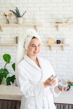 Spa and wellness. Natural cosmetics. Self care. Happy young woman applying face scrub on her face in her home kitchen