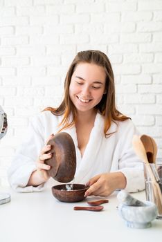 Spa and wellness. Natural cosmetics. Self care. Young caucasian woman wearing bathrobes doing spa procedures using natural cosmetics