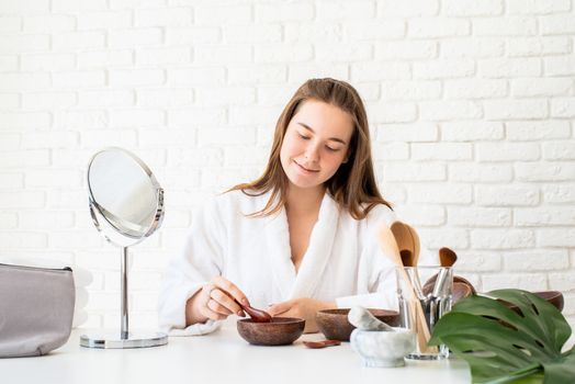 Spa and wellness. Natural cosmetics. Self care. Young caucasian woman wearing bathrobes doing spa procedures using natural cosmetics