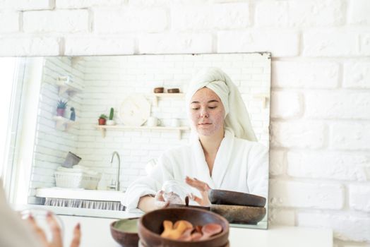 Spa and wellness. Natural cosmetics. Self care. Happy young woman applying face scrub on her face