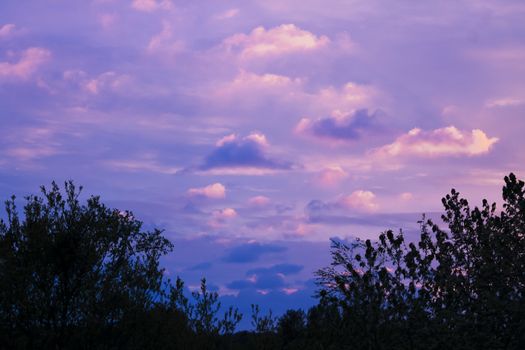 Incredible beautiful cloud formations and colors in the sky, sunset behind trees.