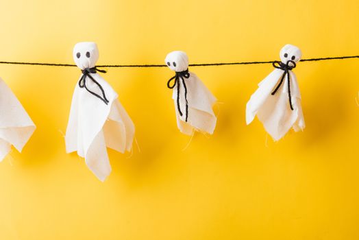 Funny Halloween day decoration party, Full body of baby cute white ghost crafts scary face hanging, studio shot isolated on yellow background, Happy holiday DIY handicraft concept