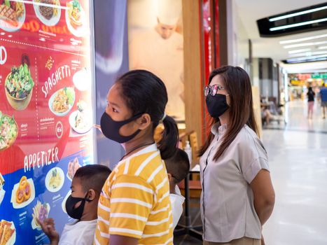 Prachinburi, Thailand 22/8/2020 Editorial illustrations Of Thai families wearing protective masks Looking at the billboard In front of a restaurant in a mall in Thailand During the time of the coronavirus outbreak in Thailand.