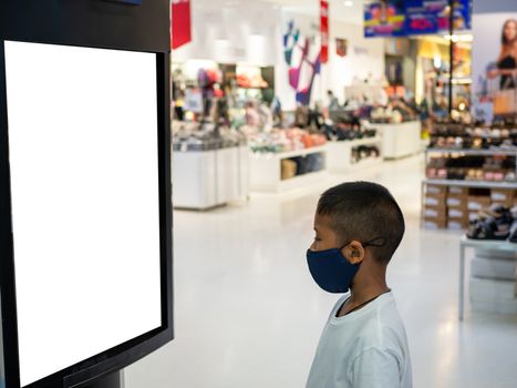 A boy wearing a mask Looking at an empty billboard in the mall