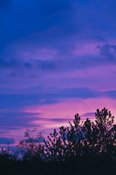 Incredible beautiful cloud formations and colors in the sky, sunset behind trees.