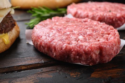 Ground beef organic cutlets on dark wooden background.