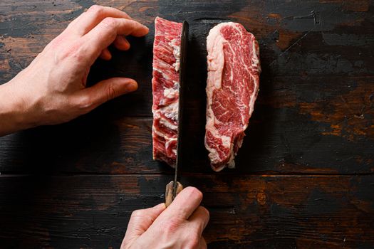 Raw Chuck eye roll black angus marbled beef steak on vintage dark wood table Organic beef. with butcher hands and meat cleaver at work chop.