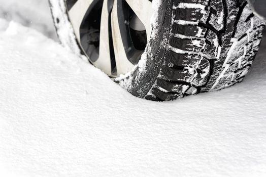 Winter tire in snow closeup. Car in the snow