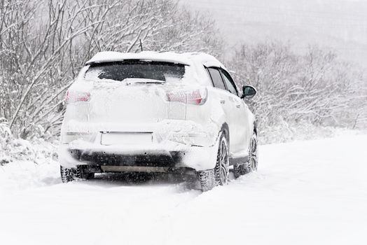 Blizzard. Car in the snow. Winter road after snowfall