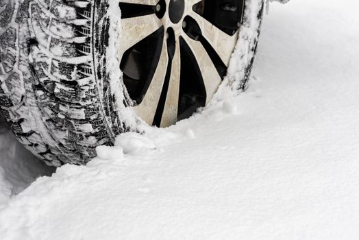 Car in the snow. Closeup of car tires in winter on the road covered with snow