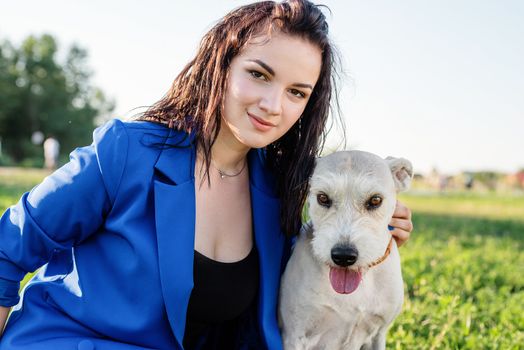 Pet care. Pet adoption. Beautiful young woman in sitting in grass with her mixed-breed dog pet