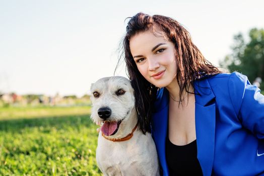 Pet care. Pet adoption. Beautiful young woman in sitting in grass with her mixed-breed dog pet