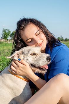 Pet care. Pet adoption. Young woman playing and hugging her dog in the park