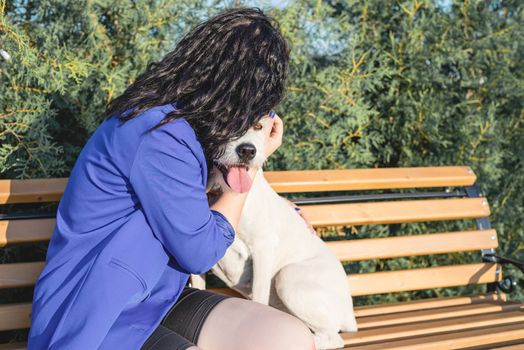 Pet care. Pet adoption. Young woman playing and hugging her dog in the park